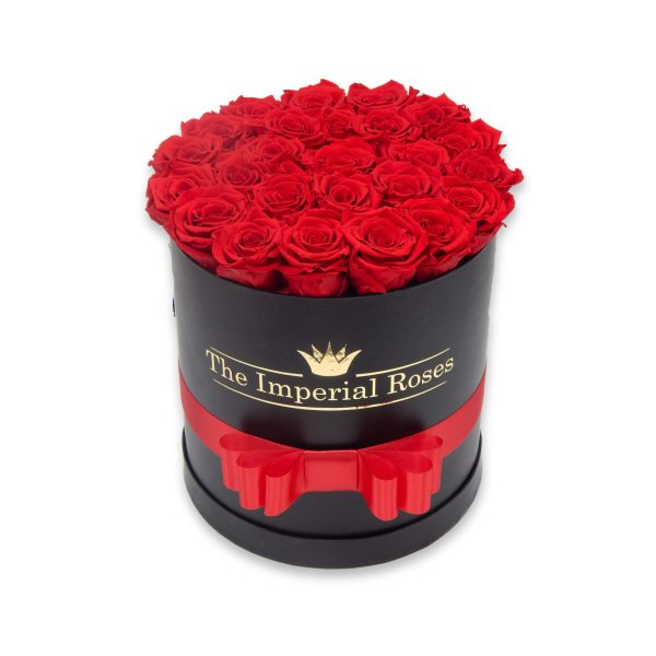 okruhly čierny flowerbox s červenými stabilizovanými ružami luxusnou červenou stuhou a zlatým lesklým logom The Imperial Roses